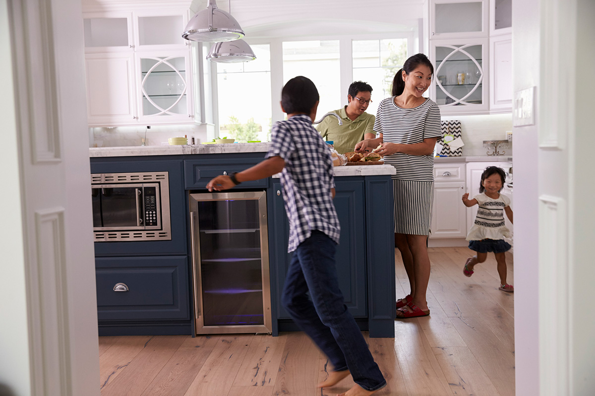 Parents Prepare Food As Children Play In Kitchen trico homes calgary homebuilder new homes for sale